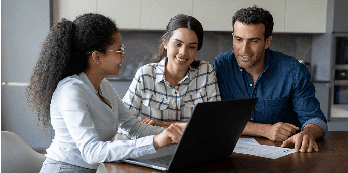 Three people discussing over a laptop.