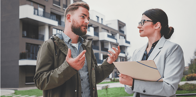 Man and woman discussing outside modern buildings.