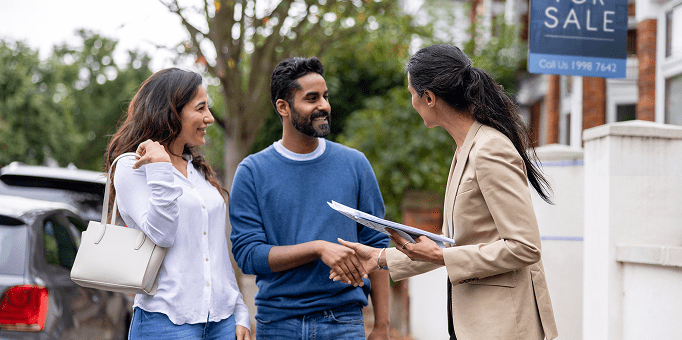 Couple meeting real estate agent, shaking hands.