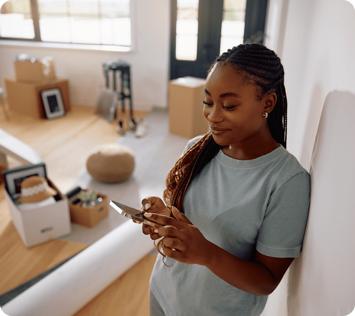 Woman texting in new apartment with boxes.