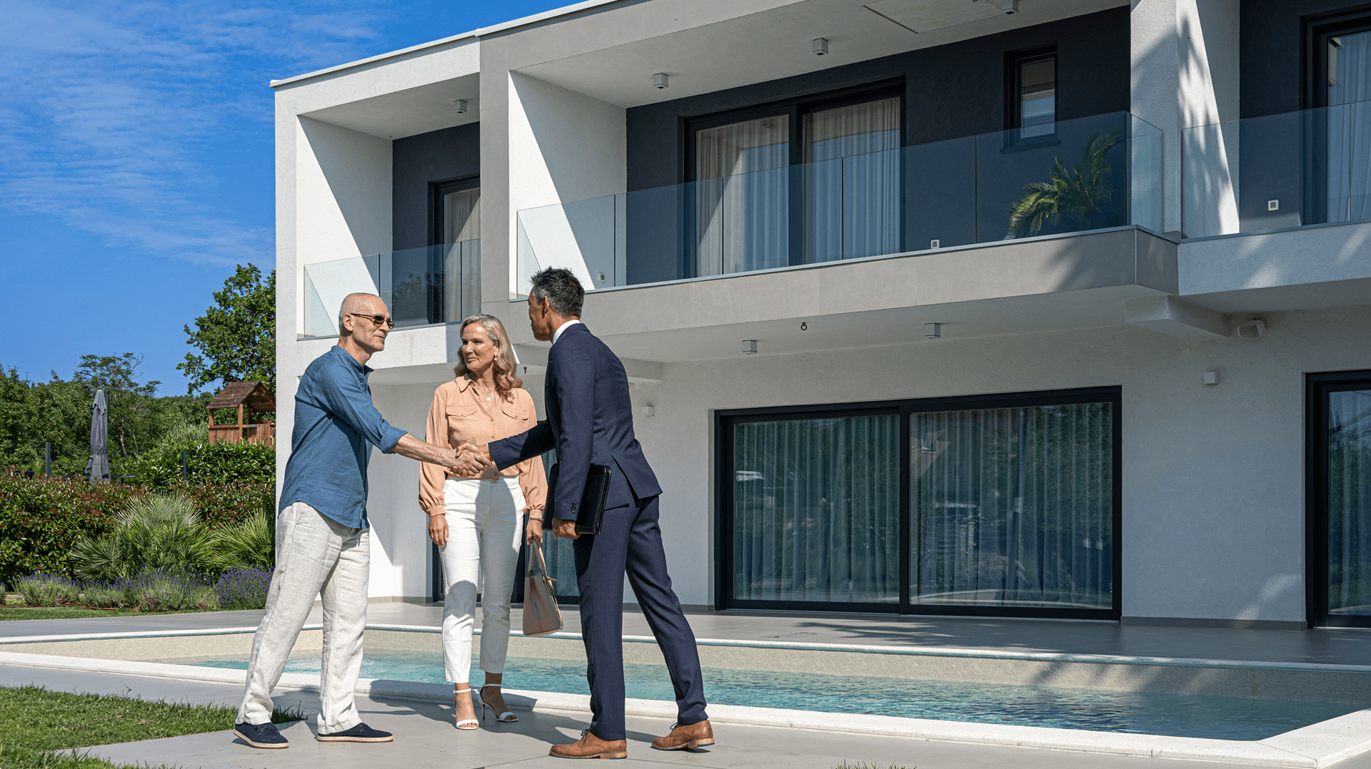 People shaking hands outside modern house.